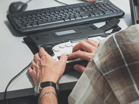Blind man operating a braille device on a computer